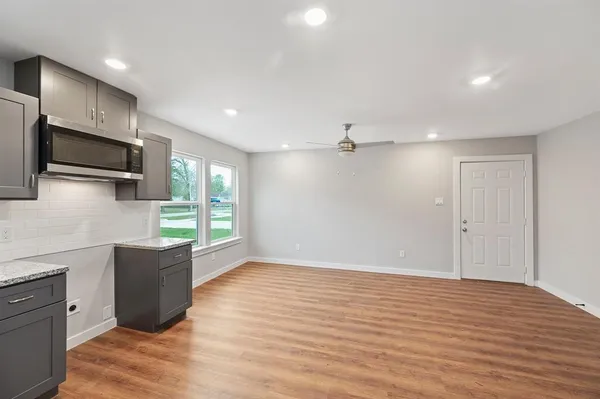 a view of an empty room with a window and wooden floor