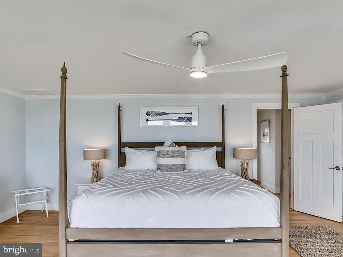 21642 Chicken Point Road Tilghman, MD 21671 - Photo 26 of 63 a bedroom with a large bed and a chandelier