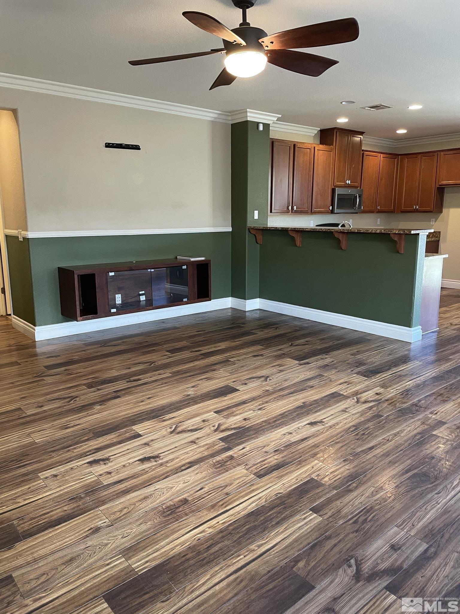 8945 Convair Way Reno, NV 89506 - Photo 4 of 26 an empty room with wooden floor a ceiling fan and kitchen view