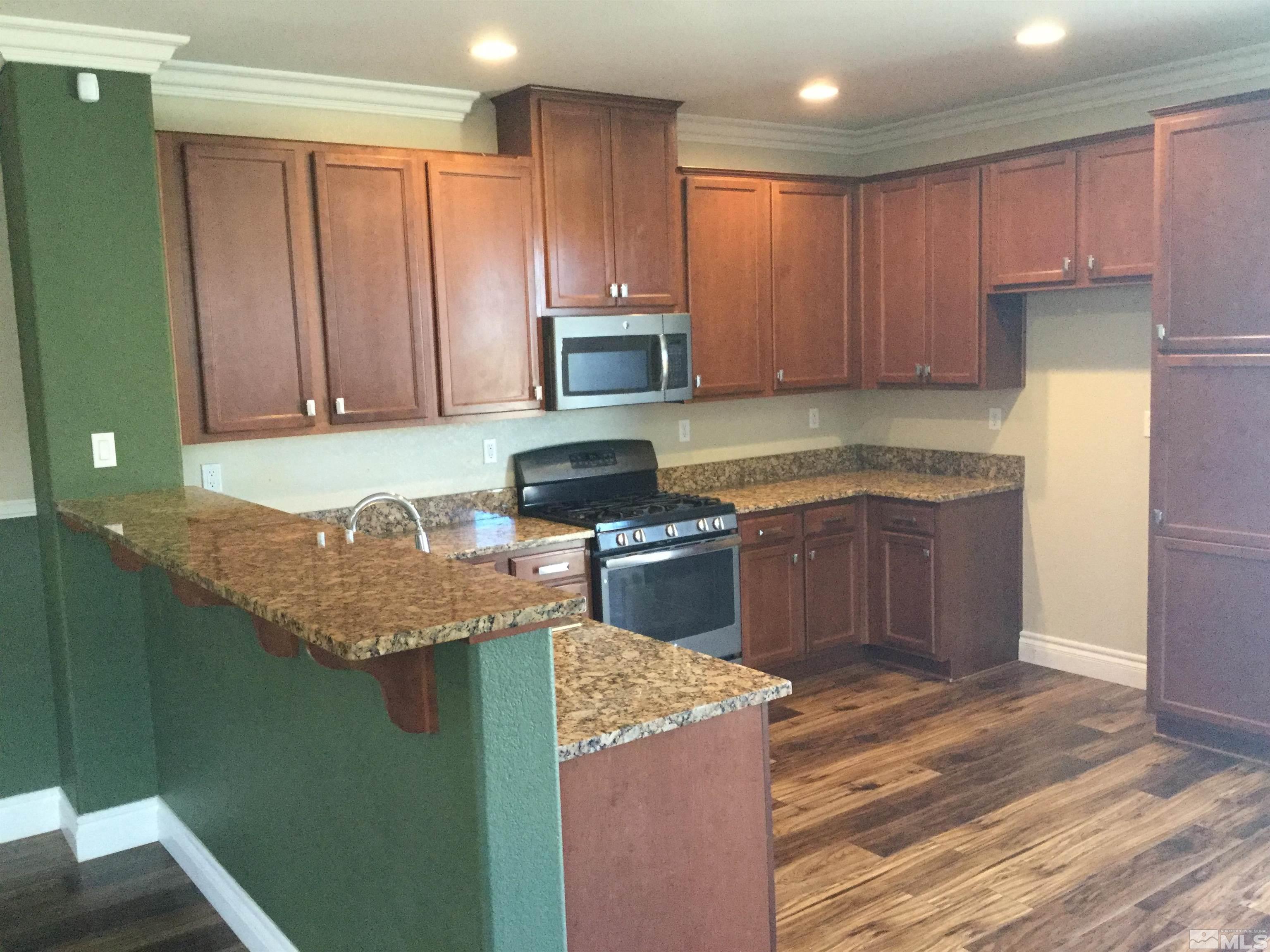 8945 Convair Way Reno, NV 89506 - Photo 8 of 26 a kitchen with granite countertop wooden cabinets and stainless steel appliances