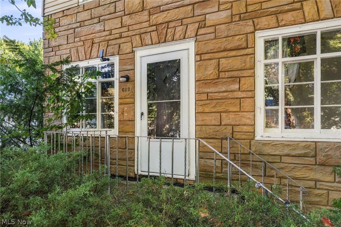 619 Garry Road Akron, OH 44305 - Photo 2 of 28 Stone veneer exterior with multiple window panes and a storm door entry