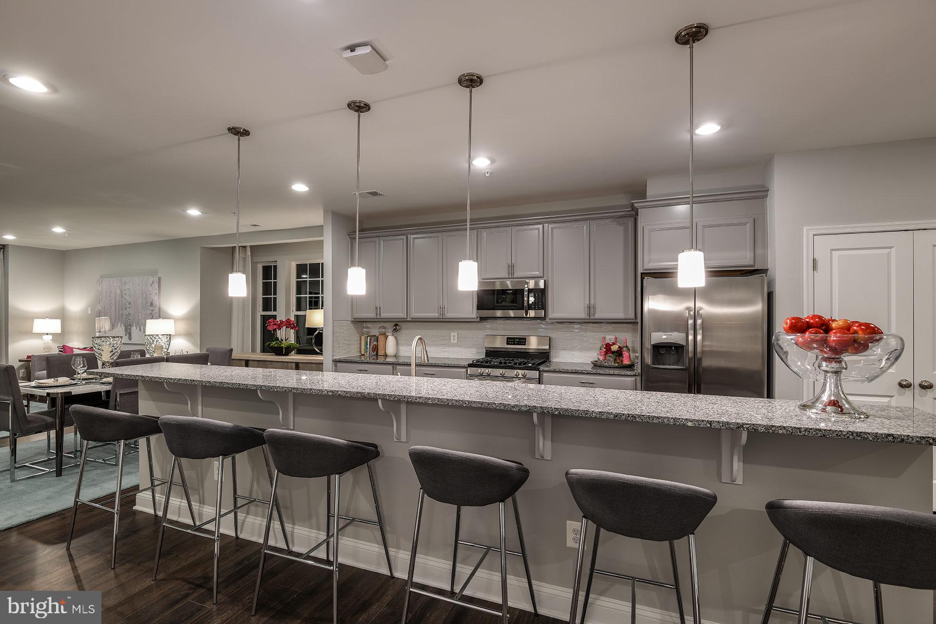 7103 Delegate Place Frederick, MD 21703 - Photo 2 of 23 a kitchen with stainless steel appliances a dining table chairs sink and cabinets
