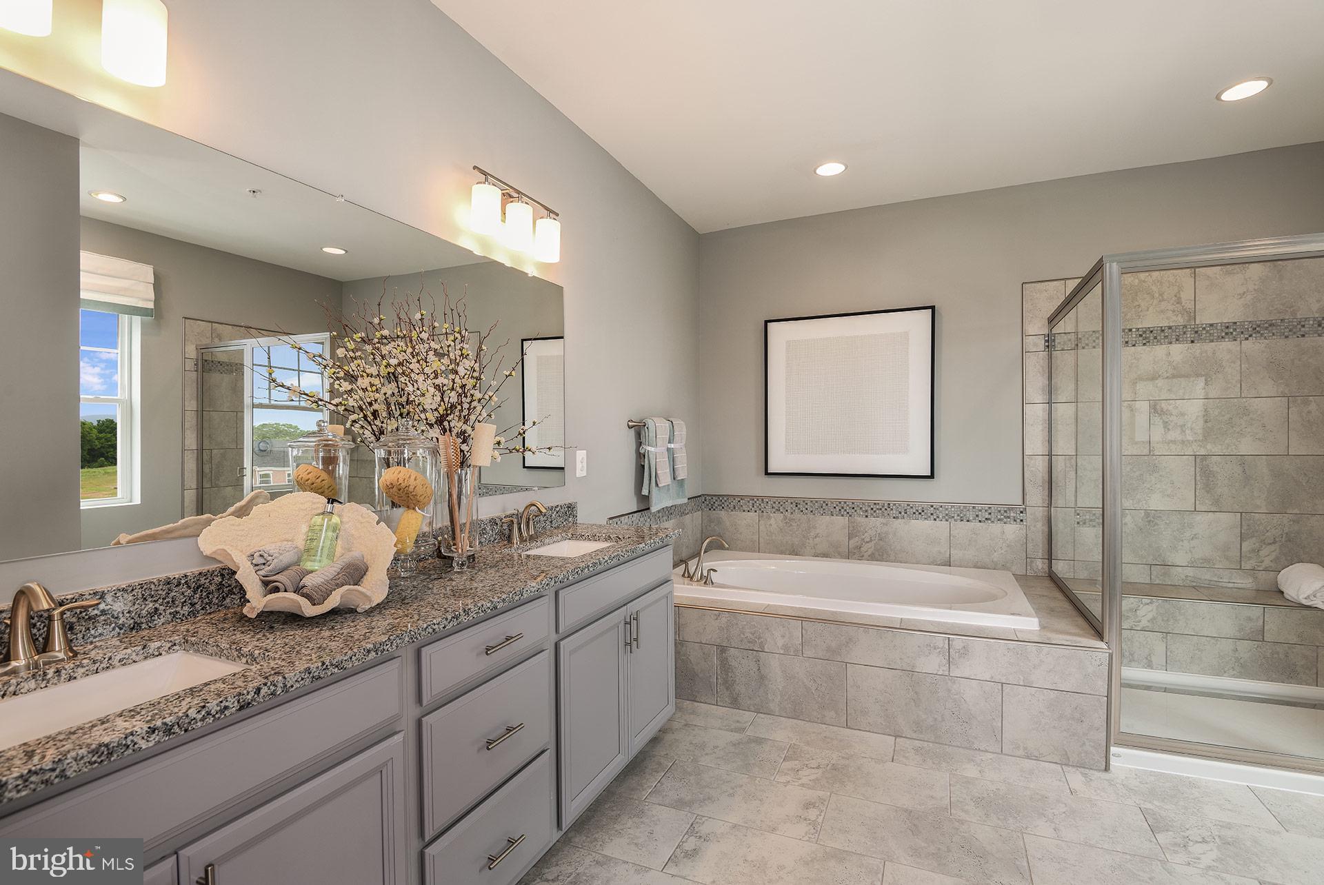 7103 Delegate Place Frederick, MD 21703 - Photo 12 of 23 a spacious bathroom with a double vanity sink a mirror and a bathtub