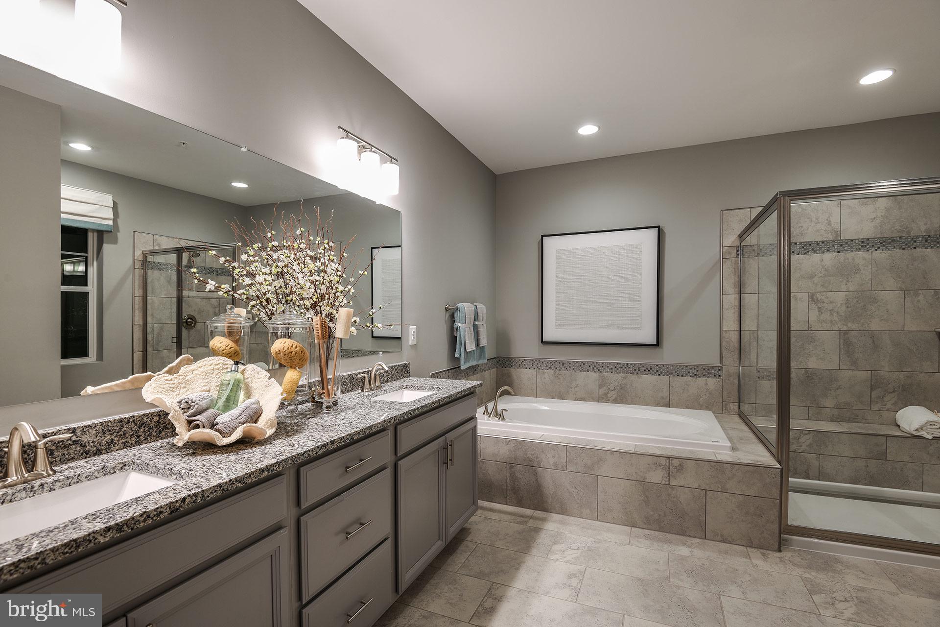 7103 Delegate Place Frederick, MD 21703 - Photo 16 of 23 a spacious bathroom with a double vanity sink a mirror and a bathtub