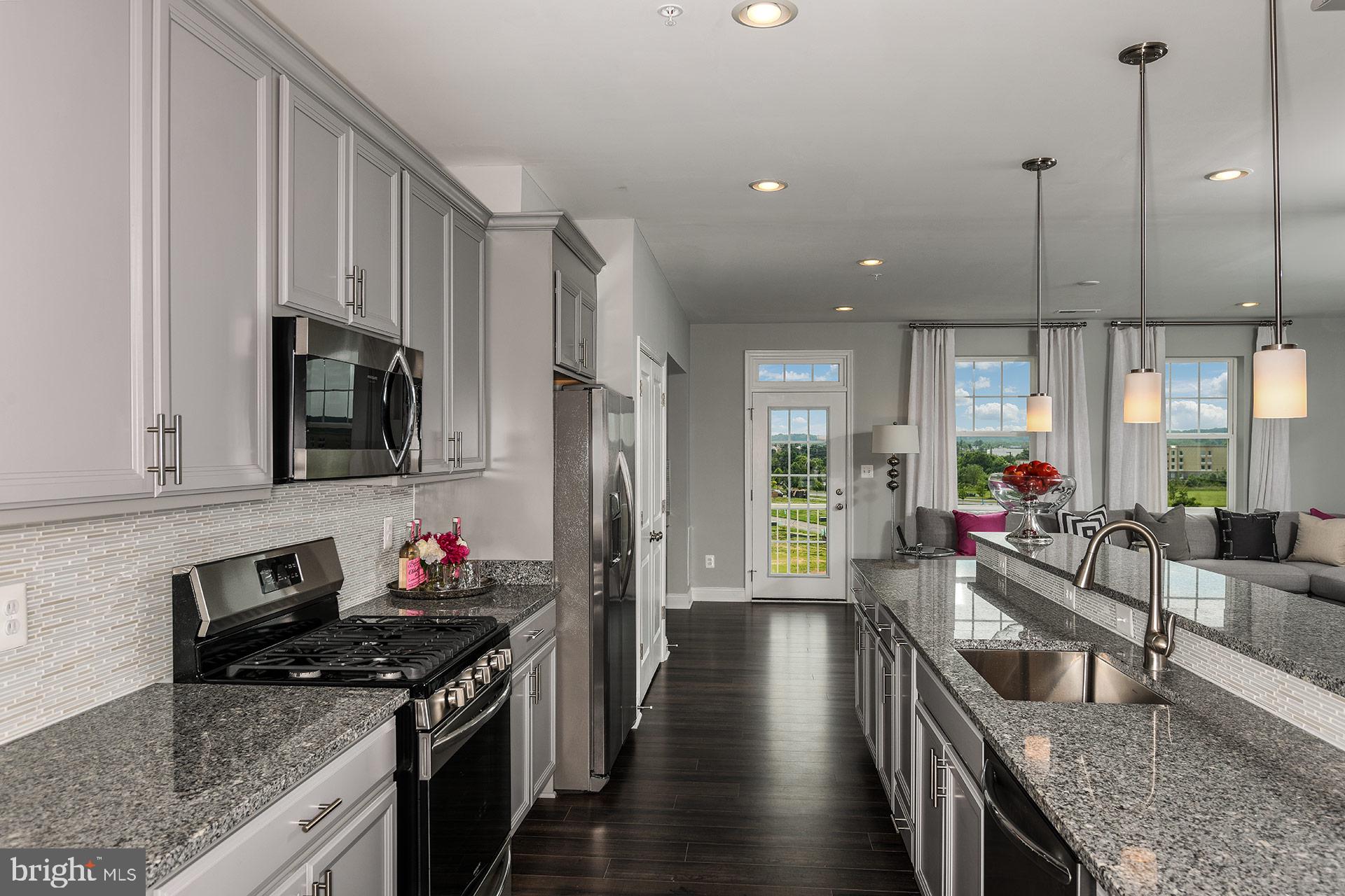 7103 Delegate Place Frederick, MD 21703 - Photo 4 of 23 a kitchen with granite countertop a stove and a view of living room