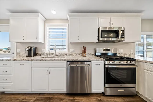 a kitchen with stainless steel appliances granite countertop a stove a sink and a microwave
