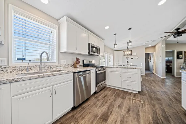 a kitchen with granite countertop a sink cabinets stainless steel appliances and a window