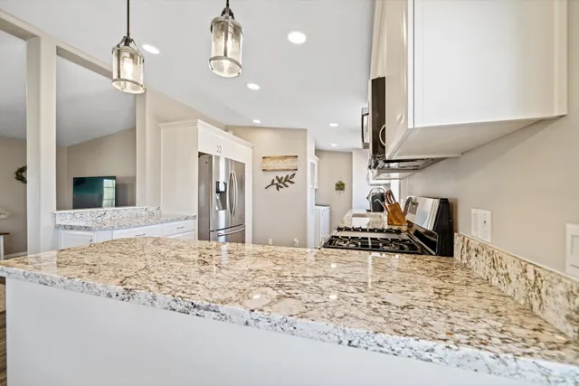 a view of a kitchen with kitchen island a sink stainless steel appliances and cabinets
