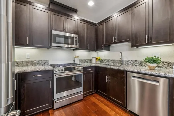 a kitchen with granite countertop a sink cabinets and wooden floor
