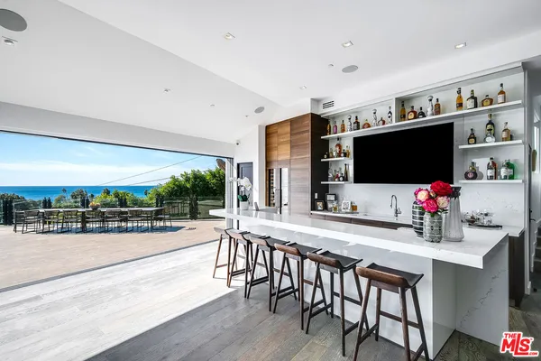 a room with stainless steel appliances kitchen island granite countertop a table chairs and a refrigerator