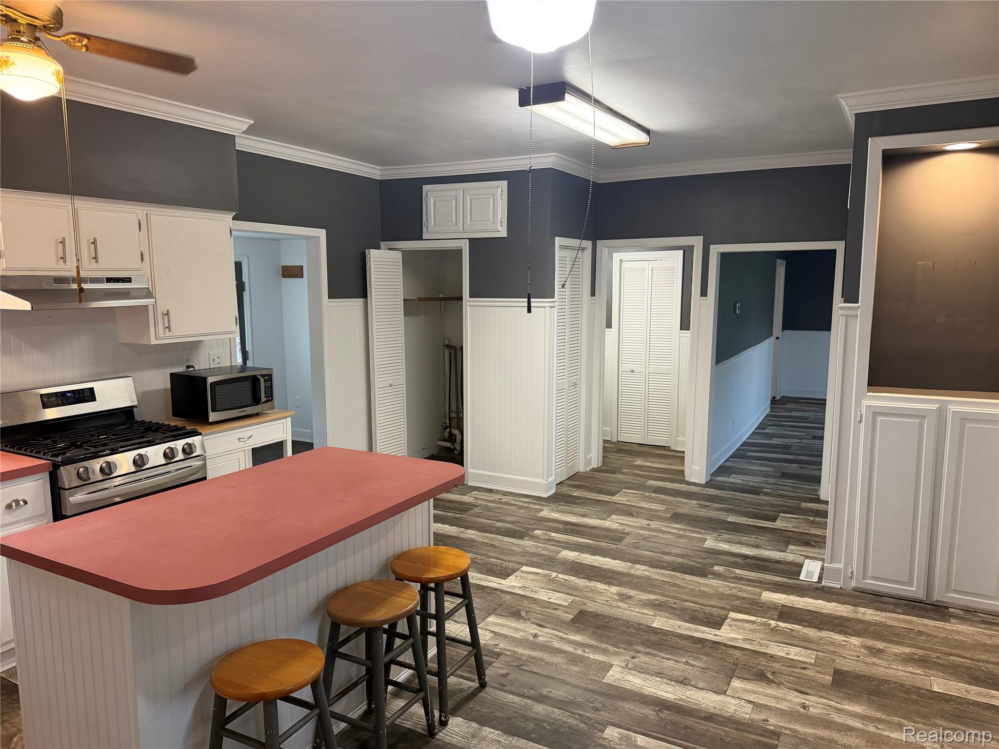 2402 Mertz Road Caro, MI 48723 - Photo 9 of 26 Kitchen featuring a gas range, white cabinetry, a central island with a red countertop, and wood-finish flooring