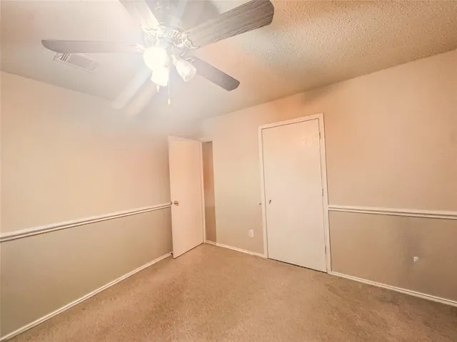 an empty room with chandelier fan and closet area