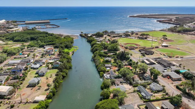 an aerial view of ocean and residential houses with outdoor space