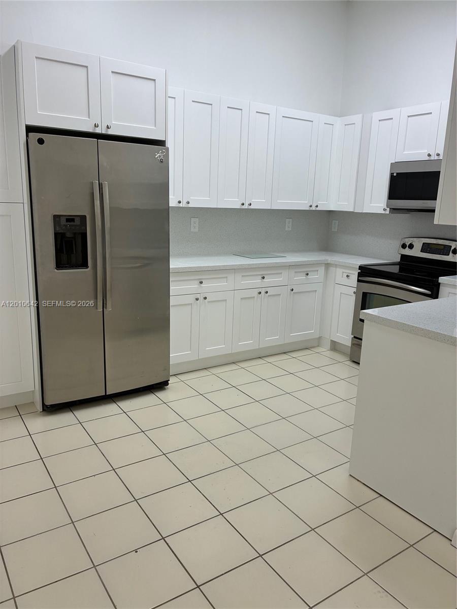 7640 Southwest 153rd Court, Unit 207 Miami, FL 33193 - Photo 4 of 8 a kitchen with a refrigerator and white cabinets