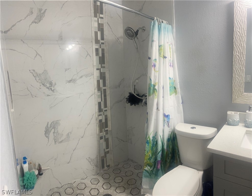 941 Happy Road North Fort Myers, FL 33903 - Photo 10 of 19 a white toilet sitting next to a shower curtain