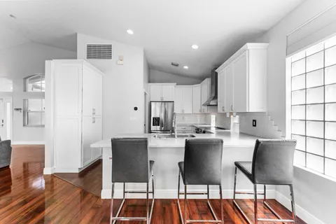 a kitchen with stainless steel appliances kitchen island granite countertop a dining table chairs and white cabinets