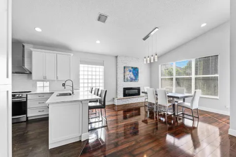 a kitchen with stainless steel appliances granite countertop a stove top oven a sink dishwasher a dining table and chairs with wooden floor