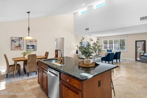 a kitchen with stainless steel appliances granite countertop a stove top oven a sink a dining table and chairs with wooden floor