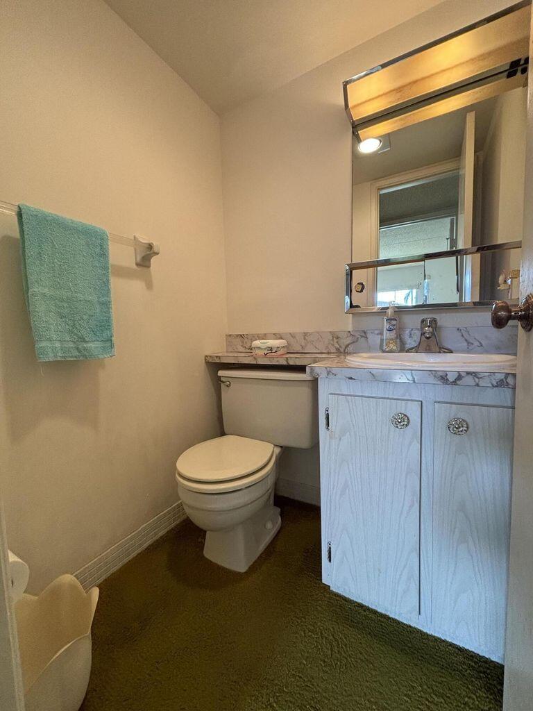 3400 Springdale Boulevard, Unit 217 Palm Springs, FL 33461 - Photo 8 of 15 a bathroom with a granite countertop toilet sink and mirror