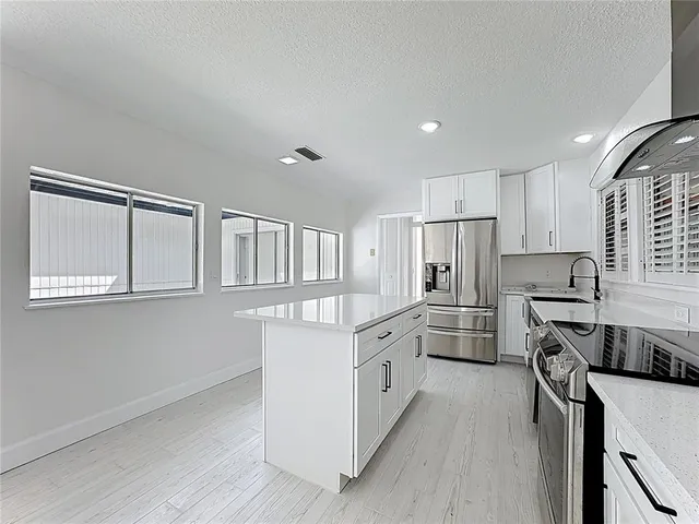 a view of kitchen with stainless steel appliances kitchen island wooden floor and window