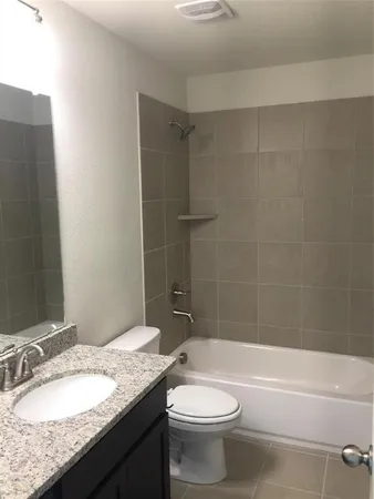 a bathroom with a granite countertop sink a toilet and shower