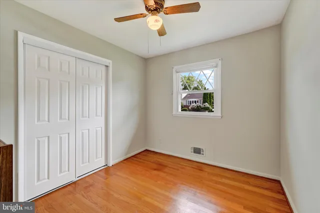 an empty room with wooden floor chandelier fan and windows