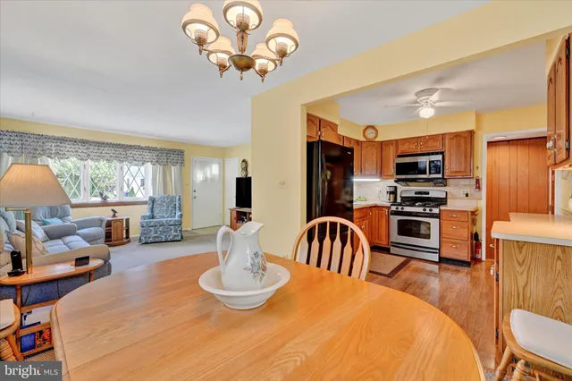 a dining room with furniture a kitchen wooden floor and a chandelier