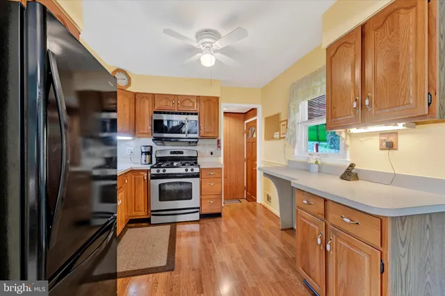 a kitchen with stainless steel appliances granite countertop a refrigerator a stove a sink and a microwave oven with wooden floor