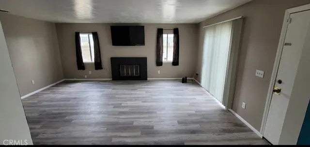 a view of an empty room with wooden floor and a window