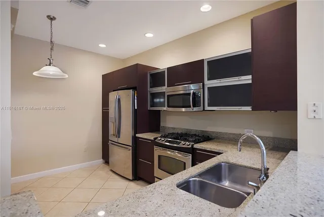 a kitchen with stainless steel appliances granite countertop a sink a stove and a refrigerator