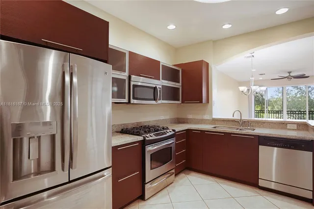 a kitchen with stainless steel appliances granite countertop a refrigerator a sink and white cabinets
