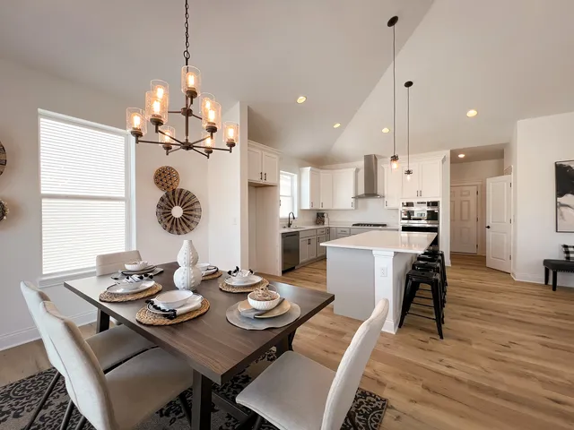 a view of a dining room and livingroom with furniture wooden floor kitchen chandelier