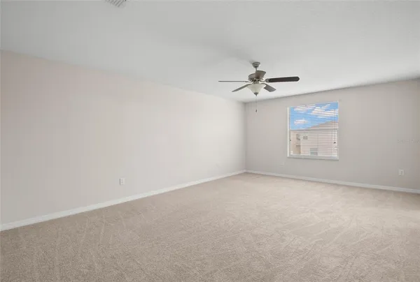 an empty room with a ceiling fan and a window