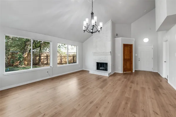 a view of a livingroom with a fireplace wooden floor and windows