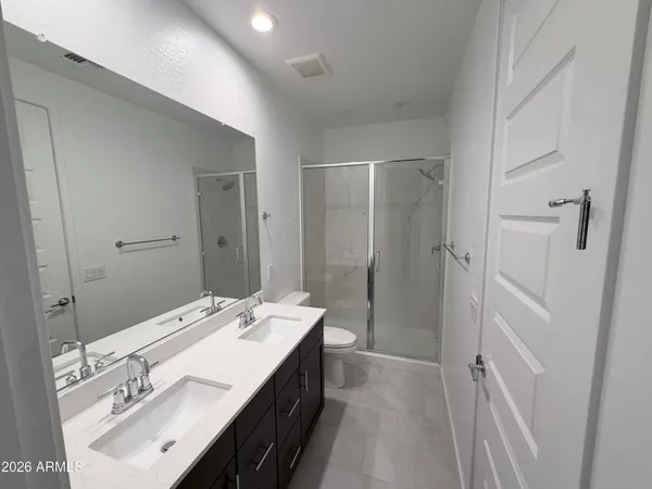 a spacious bathroom with a double vanity sink a mirror and a shower