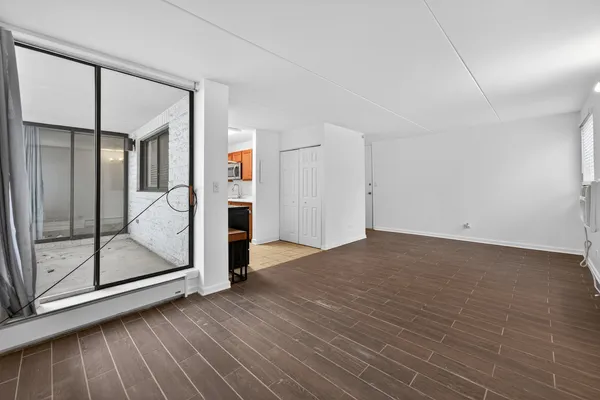 a view of empty room with wooden floor and fan