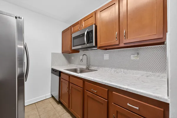 a kitchen with stainless steel appliances granite countertop a sink a microwave a refrigerator and cabinets
