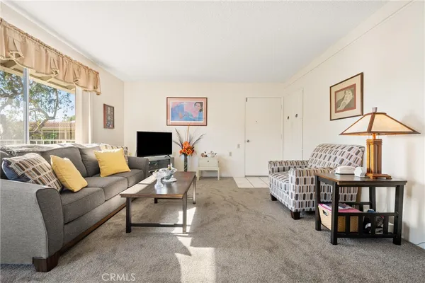 a living room with furniture a flat screen tv and a window