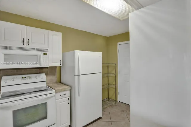 a white refrigerator freezer and a stove sitting inside of a kitchen