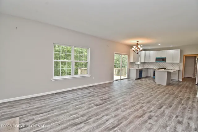 a big room with chandelier and kitchen view