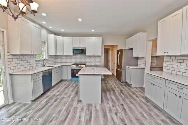 a kitchen with kitchen island granite countertop lots of counter top space a sink appliances and cabinets