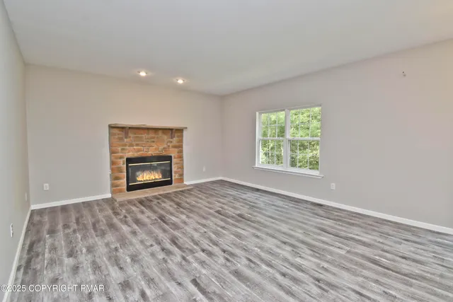 a view of empty room with wooden floor and fireplace
