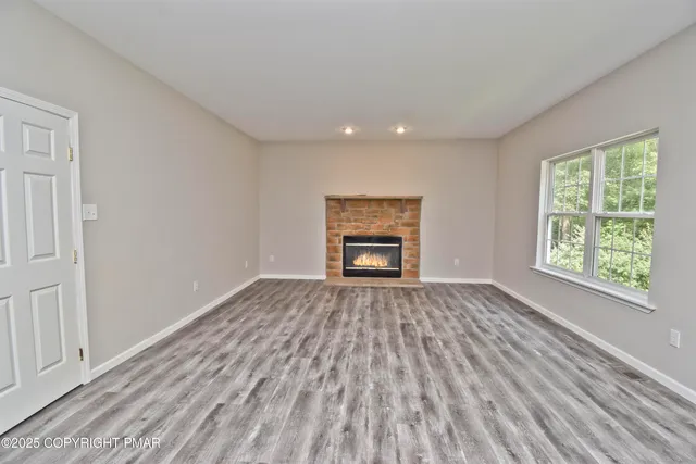 a view of empty room with wooden floor and fireplace