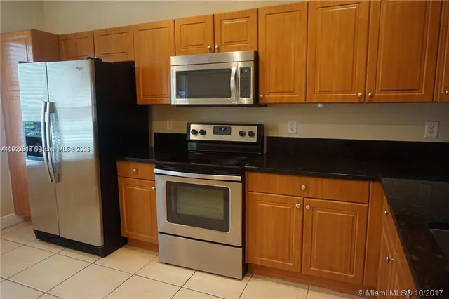 a kitchen with stainless steel appliances granite countertop a refrigerator and a stove top oven