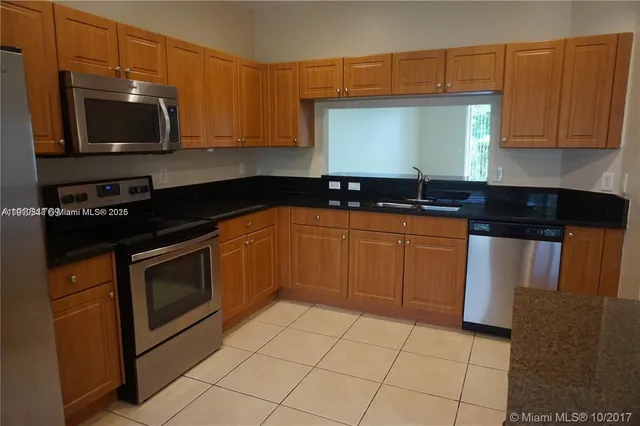 a kitchen with granite countertop a sink a stove top oven and cabinets