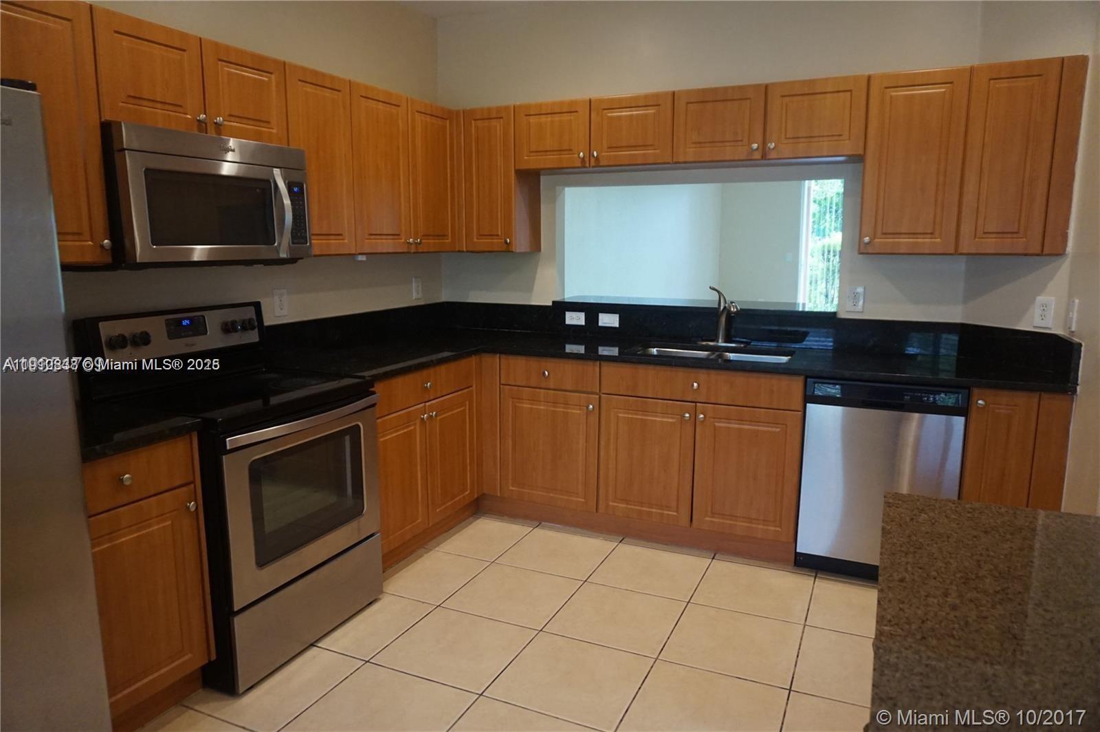 2551 Southwest 83rd Avenue, Unit 107 Miramar, FL 33025 - Photo 2 of 19 a kitchen with granite countertop a sink a stove top oven and cabinets