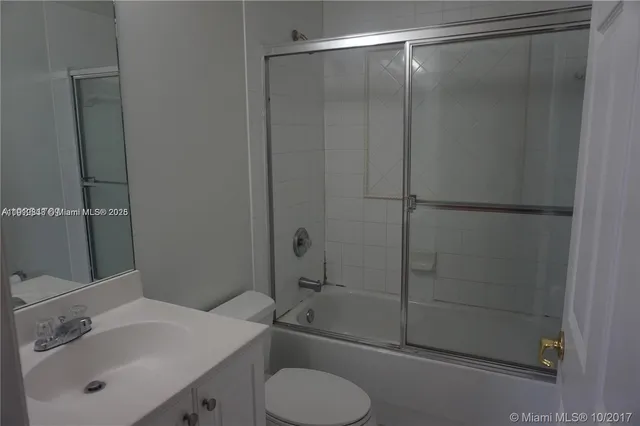a bathroom with a shower sink vanity and toilet