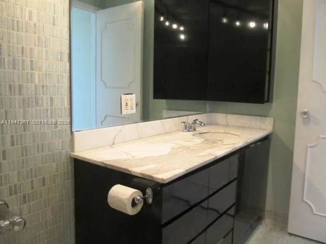 a bathroom with a granite countertop sink a mirror and vanity