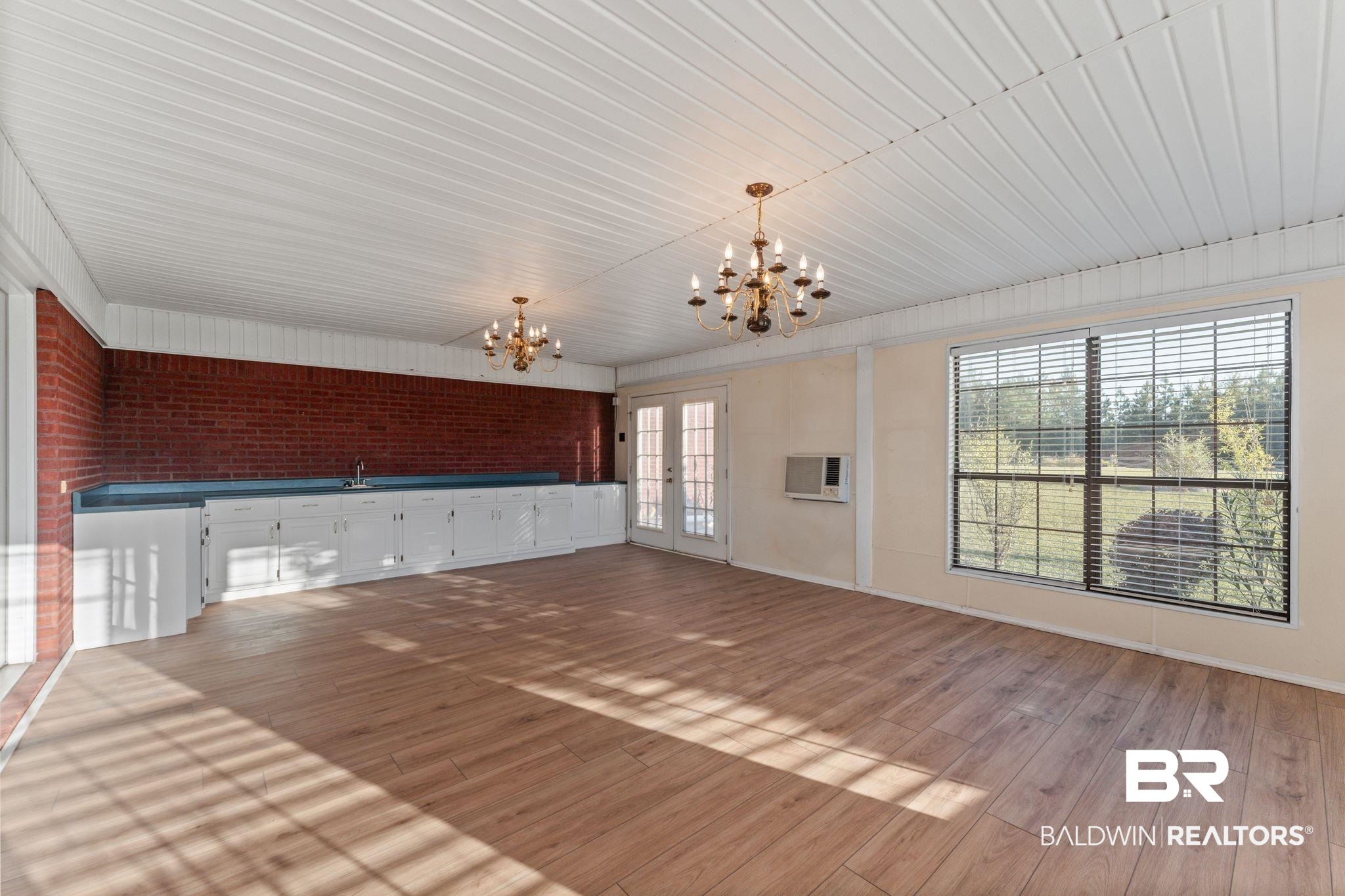 888 Mobile Cut-Off Road St. Stephens, AL 36569 - Photo 28 of 54 Unfurnished living room featuring brick wall, a chandelier, light wood finished floors, and french doors