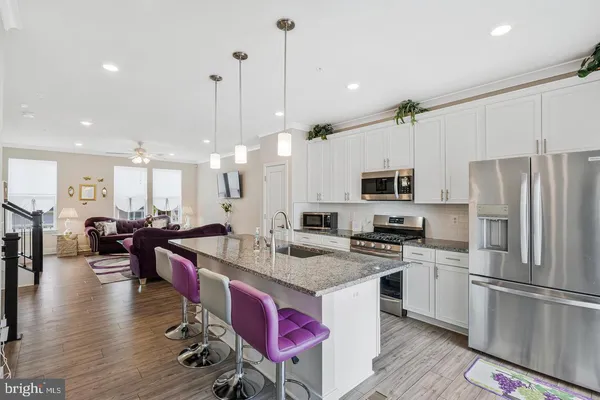 a kitchen with stainless steel appliances granite countertop a refrigerator a stove top oven a sink dishwasher and white cabinets with wooden floor